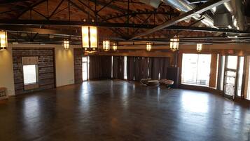 A spacious hall with a high ceiling, exposed beams, and large windows.