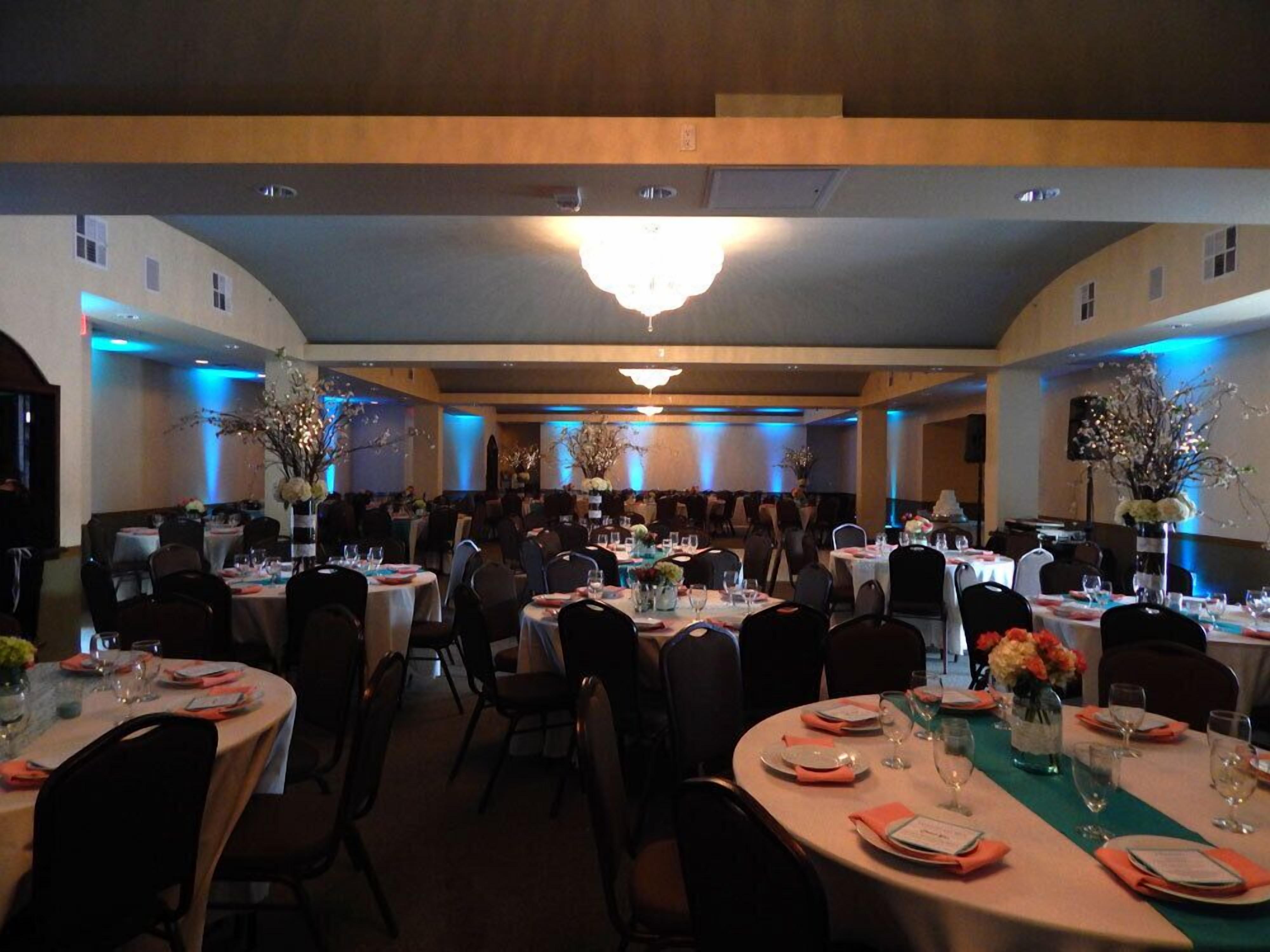 Un salón de banquetes con mesas redondas dispuestas para cenar, con centros de mesa y adornos de mesa.