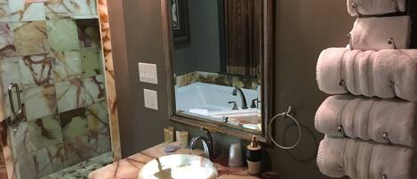 Une salle de bain avec un lavabo en marbre, un miroir, un porte-serviettes et un espace douche.