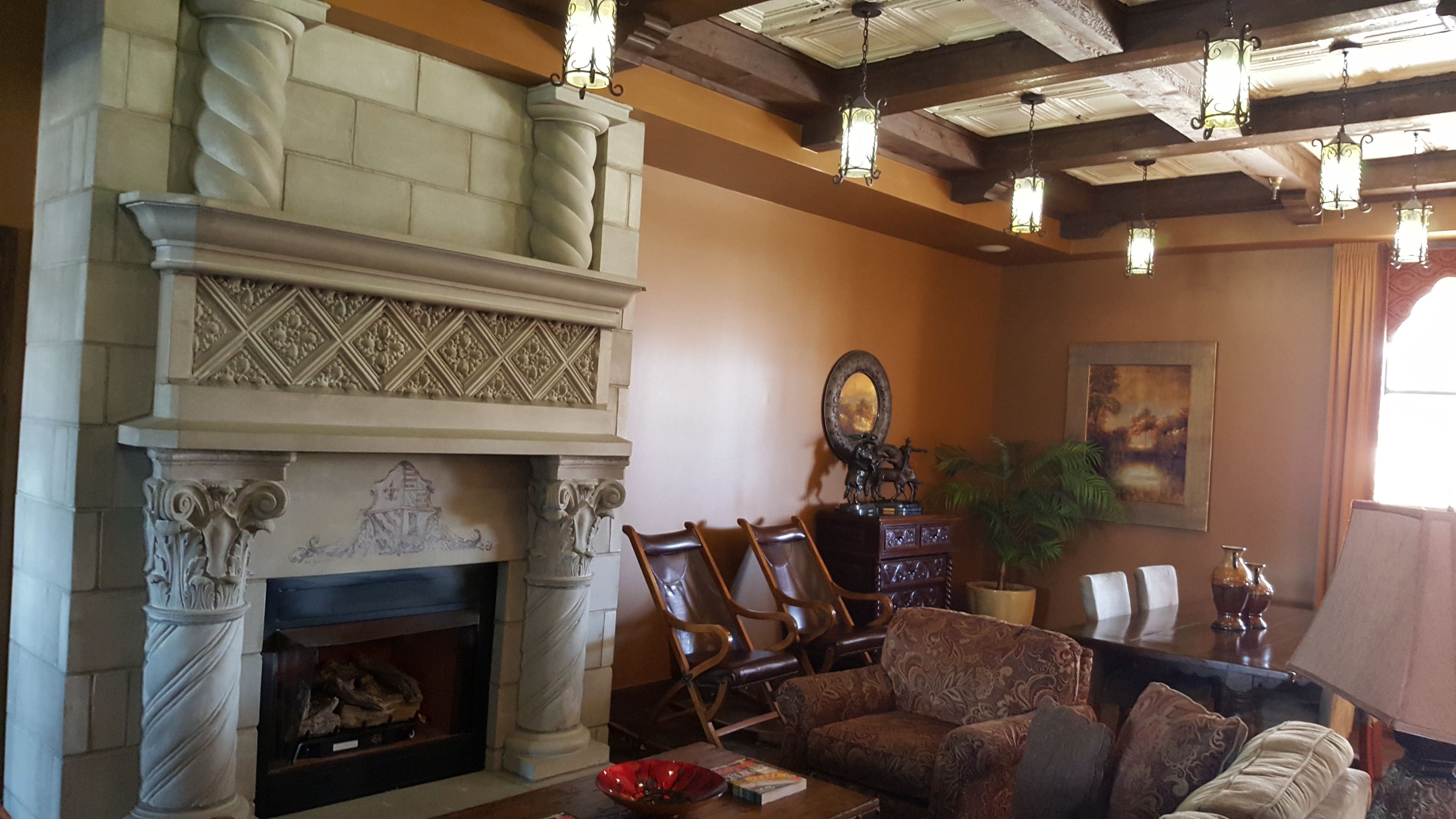 A living room with a fireplace, wooden chairs, a sofa, and a large mirror.
