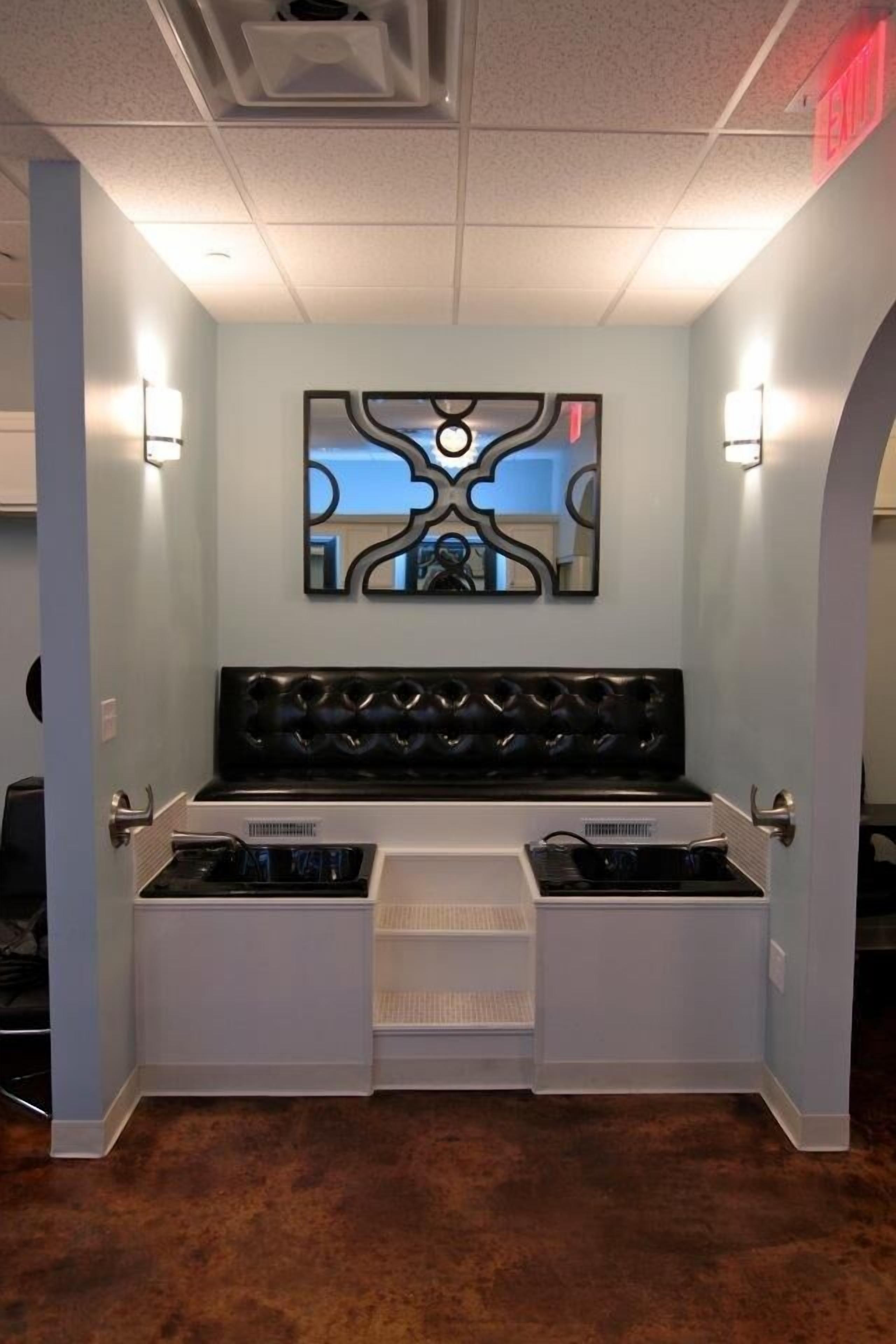 A room with a black cushioned bench, white storage units, and a wall-mounted abstract artwork.