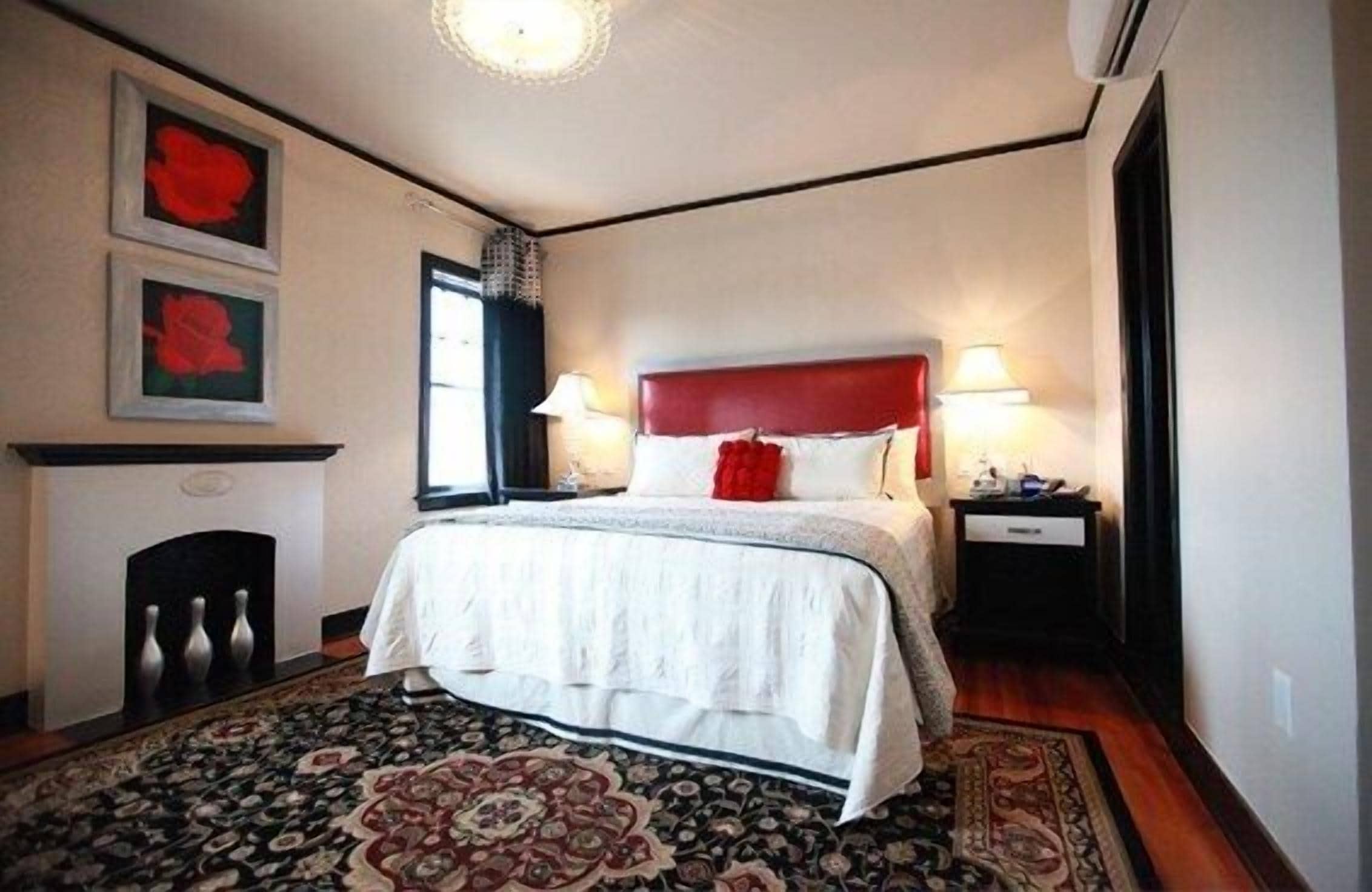 A bedroom with a large bed, a fireplace, and a rug.