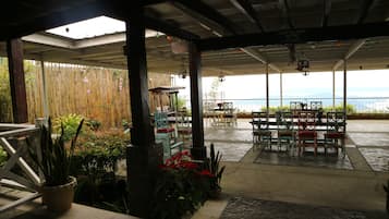 An outdoor patio area with tables and chairs, bamboo fencing, and potted plants.