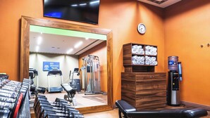 A gym with exercise equipment, a water dispenser, and a clock on the wall. - Hampton by Hilton Swinoujscie (Swinoujscie)