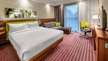 Ein Hotelzimmer mit einem großen Bett, einer Couch, einem Schreibtisch und einem Stuhl.