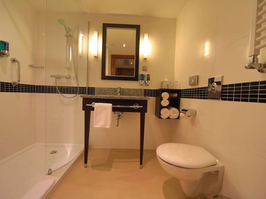 Een badkamer met een douchecabine van glas, een wastafel met een handdoek en een toilet.