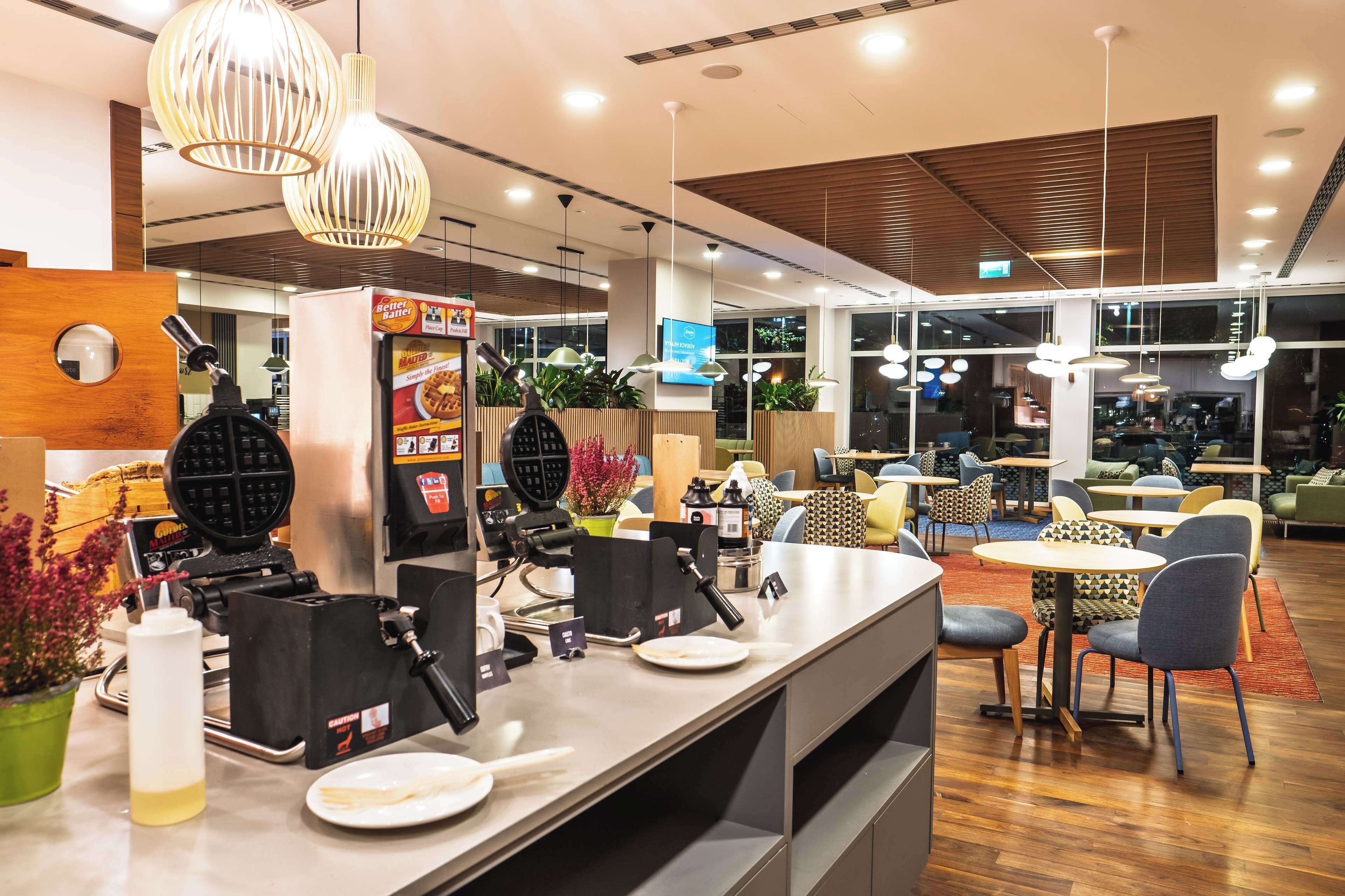 Un restaurante moderno con una máquina para gofres, zona de estar y detalles de madera.