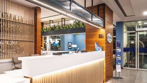 Una zona de recepción con mostrador blanco, paneles de madera y pared azul.