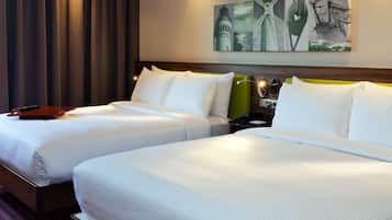 A hotel room with two beds, a nightstand, a lamp, and a painting on the wall.