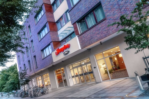 A hotel with a modern brick facade, large glass windows, and a visible reception area.
