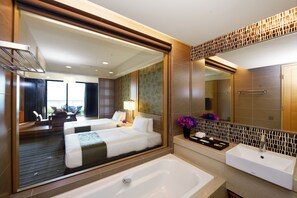 Una habitación de hotel moderna con una cama grande, un baño independiente, un balcón y vistas a la ciudad.