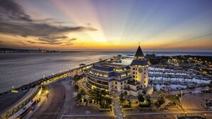 A coastal hotel with a clock tower, a marina, and a waterfront promenade.
