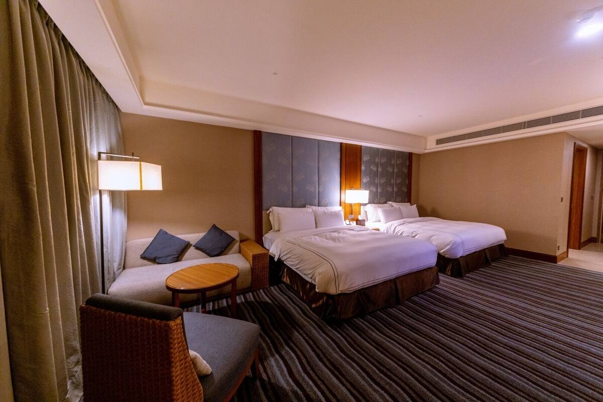 Una habitación de hotel con cama, dos mesitas de noche, un sofá y una silla.