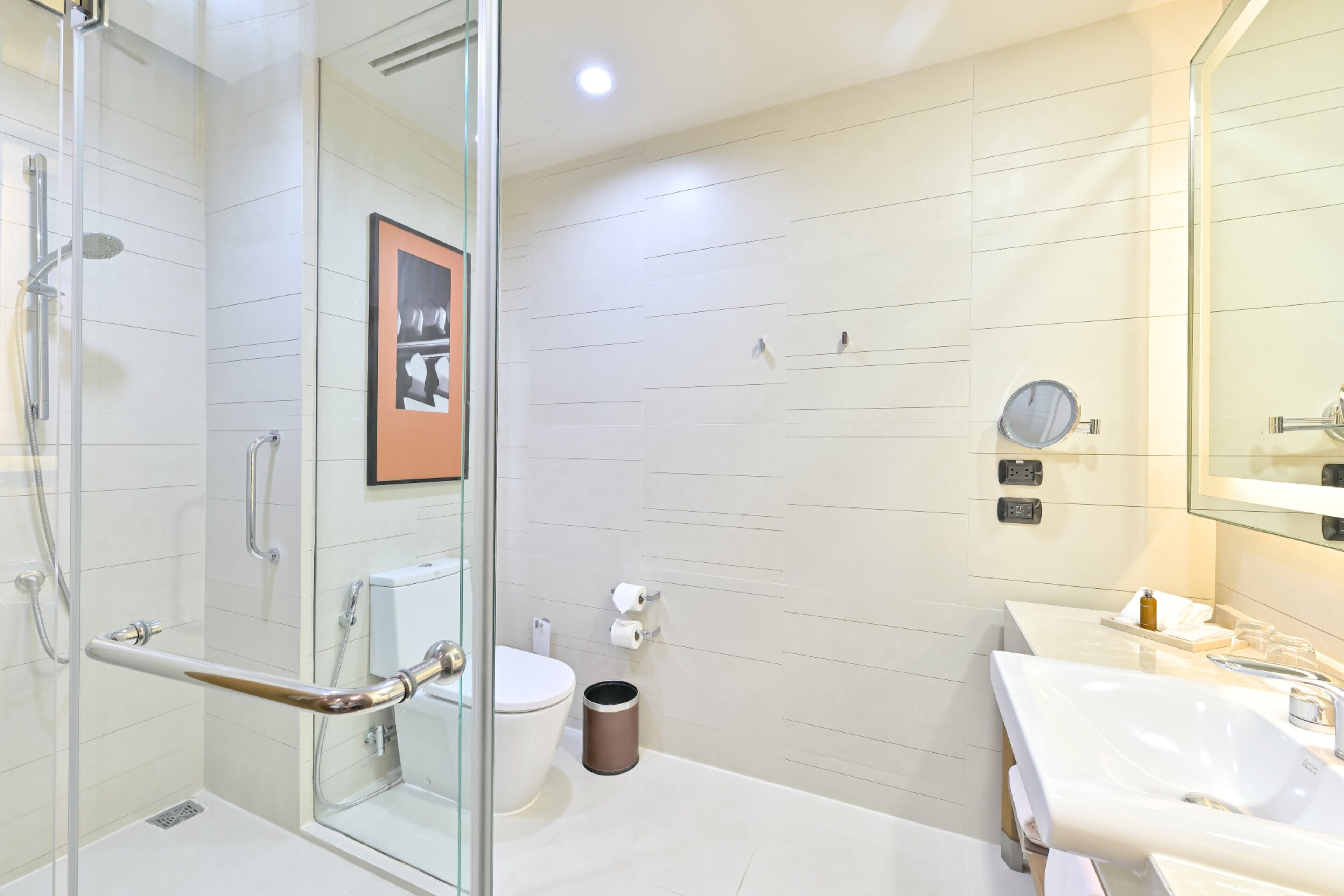 A modern bathroom with a glass shower enclosure, a white toilet, and a sink with a mirror.