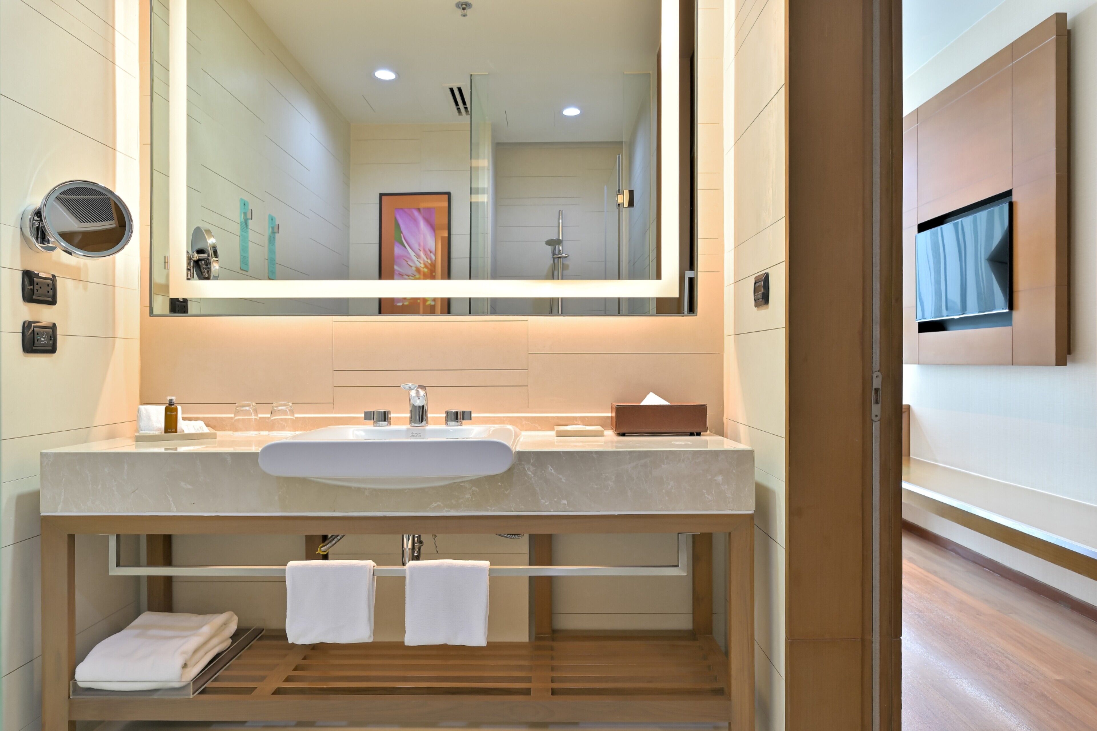 A modern bathroom with a large mirror, a sink, and a towel rack.