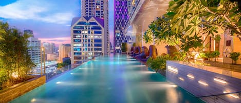 Una piscina al aire libre, sombrillas, sillones reclinables de piscina