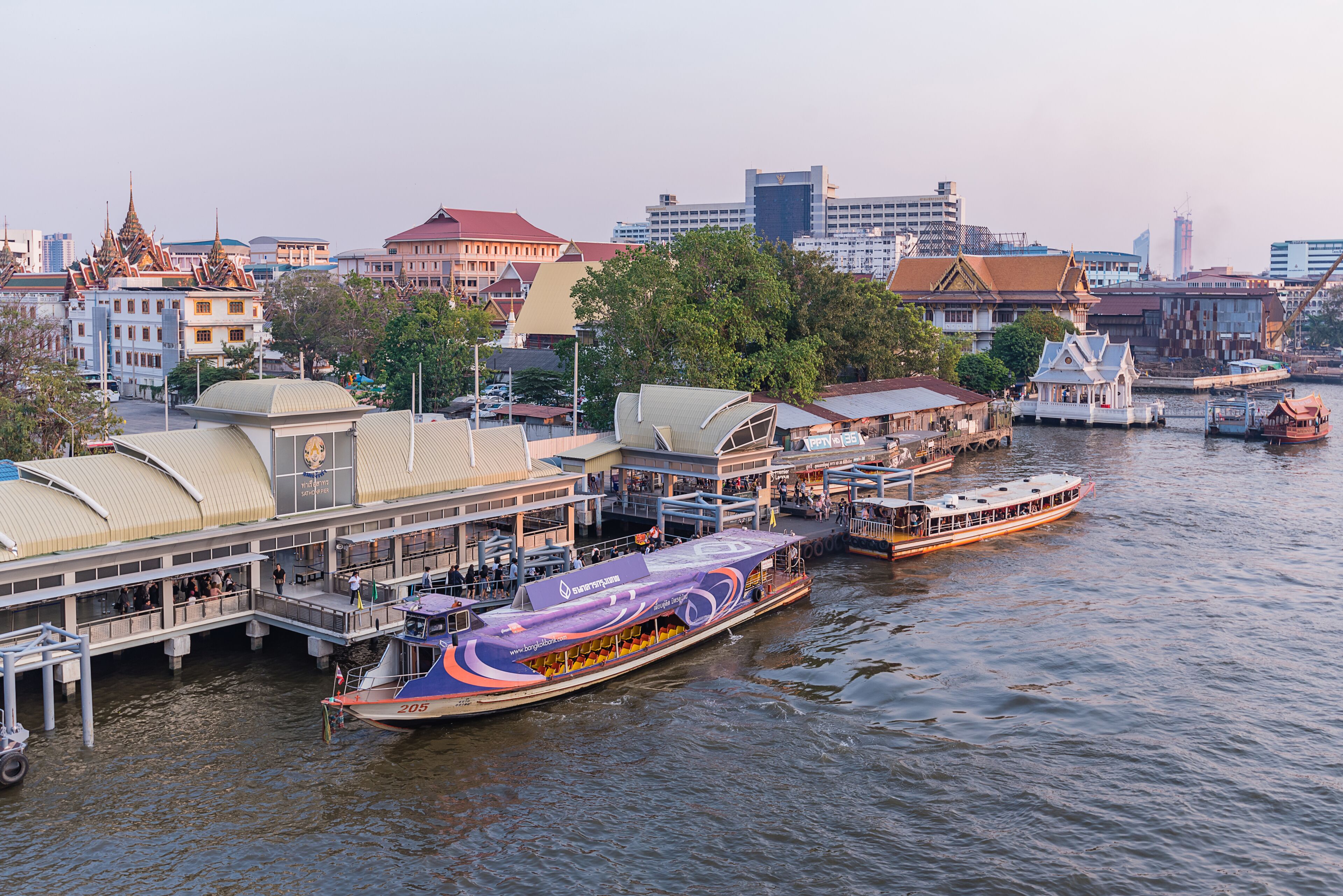 A riverfront area with a large boat docked at a pier, surrounded by buildings with traditional architecture.