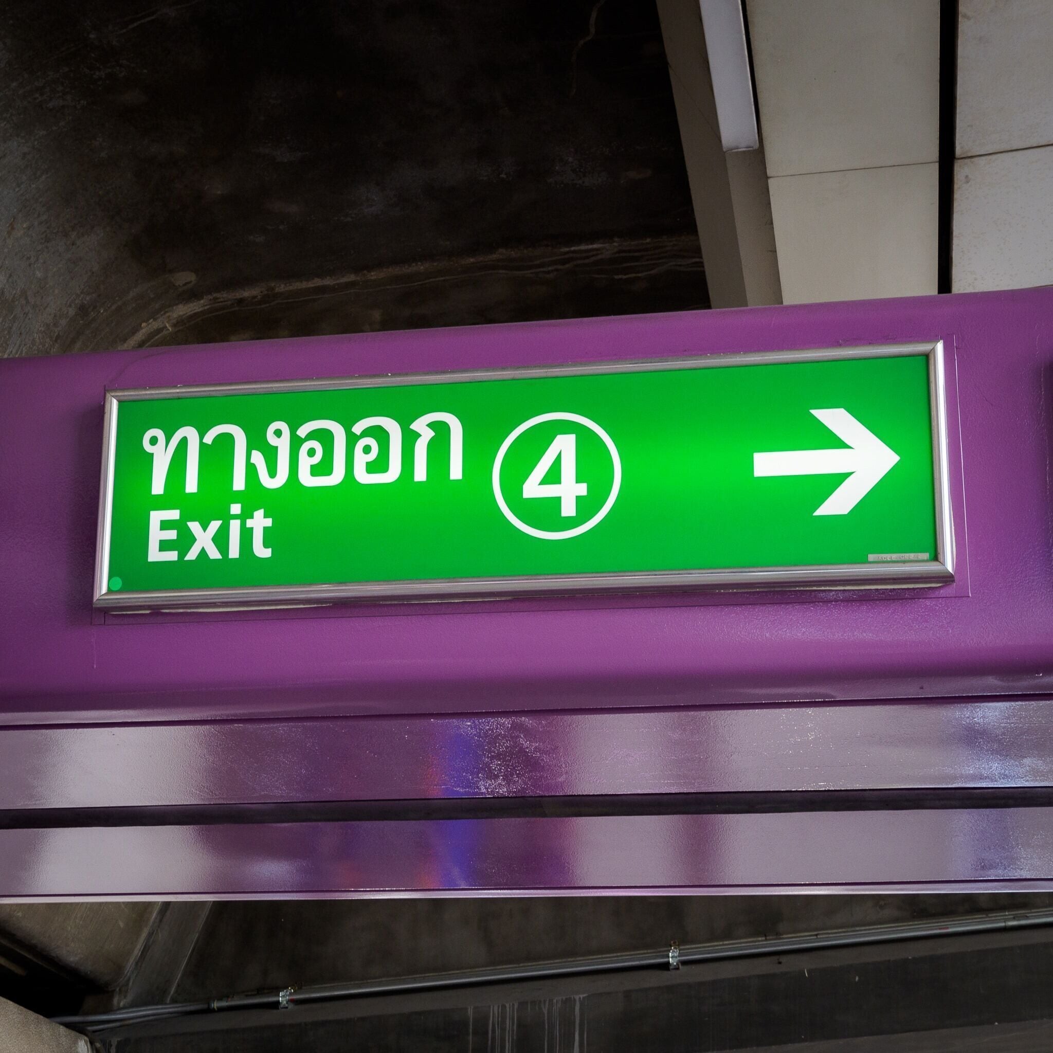 A green exit sign with white text and a white arrow pointing right.