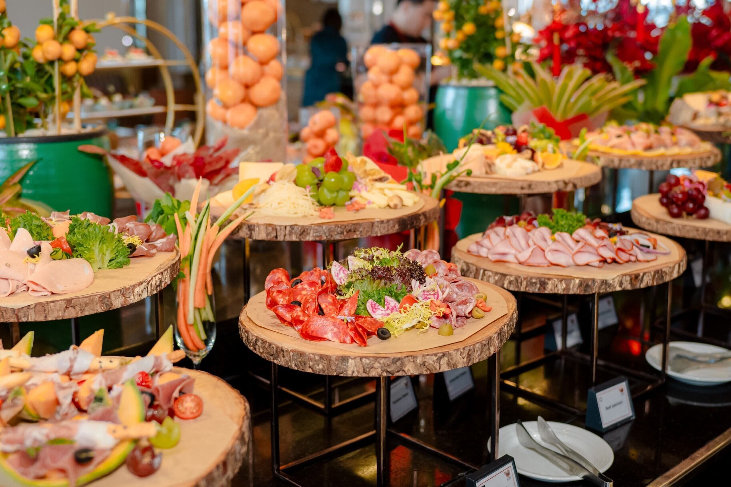 A variety of food platters on wooden stands, likely in a hotel or event setting.