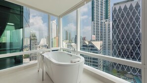 Une salle de bain moderne avec une baignoire, de grandes fenêtres et une vue sur la ville.