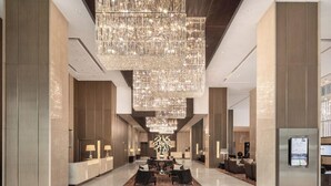 Un hall d’entrée spacieux, agrémenté d’un grand lustre, d’un comptoir de réception, d’un espace salon et d’un comptoir d’accueil moderne.