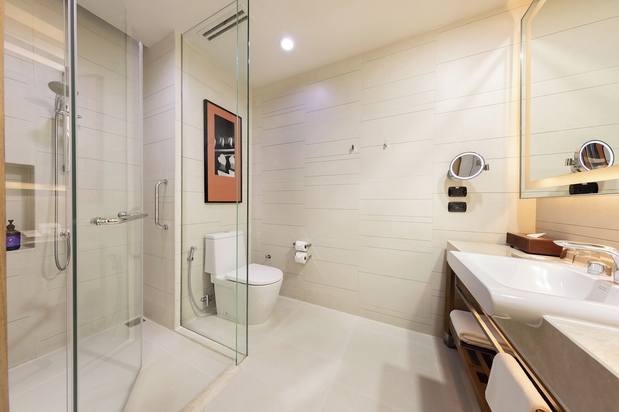 A modern bathroom with a glass-enclosed shower, a toilet, a sink with a vanity, and a mirror with a light.