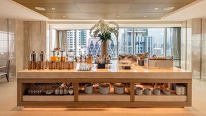 Een moderne hotelreceptie met een groot aanrecht, glazen en uitzicht op de skyline.