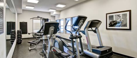 Una palestra con tapis roulant, ellittiche e panche per pesi.