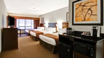 A hotel room with two beds, a desk with a computer, a coffee maker, and a TV.