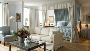 Un dormitorio con cama con dosel, un sofá, una mesa de centro y un jarrón con flores.