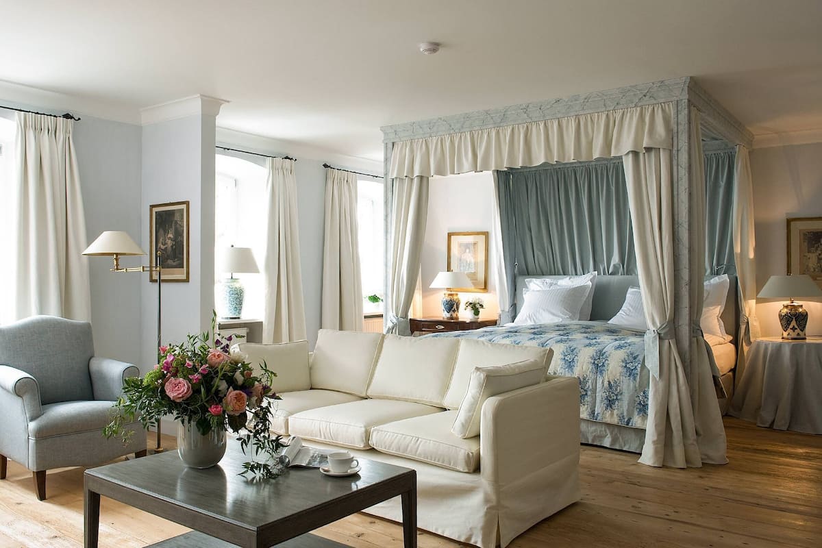 Une chambre à coucher avec un lit à baldaquin, un canapé, une table basse et un vase de fleurs.