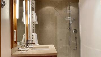 Un baño moderno con tocador de madera, cabina de ducha de vidrio y un espejo grande.