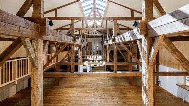 Un interior espacioso con altos vigas de madera, un tragaluz y un candelabro central.