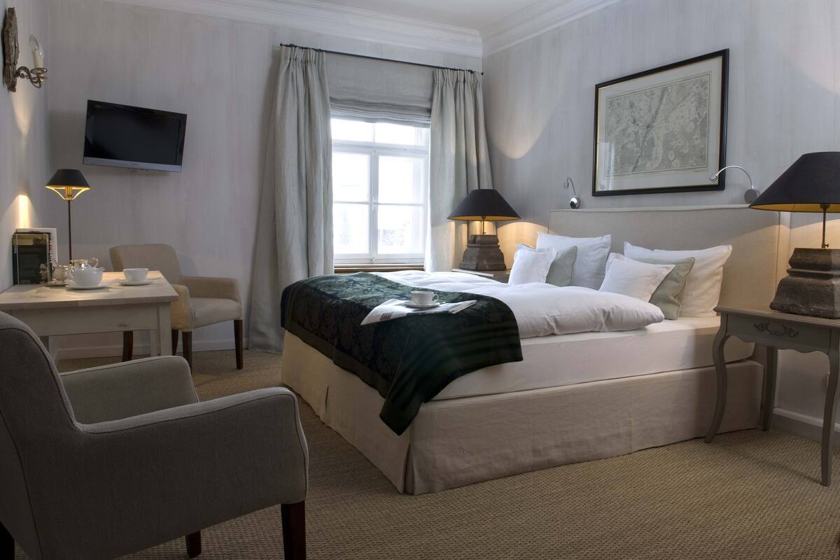 Une chambre d’hôtel comprenant un lit, un bureau avec une chaise, une télévision et une lampe.