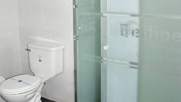 Une salle de bain comprenant des toilettes, une douche en verre et un porte-serviettes.
