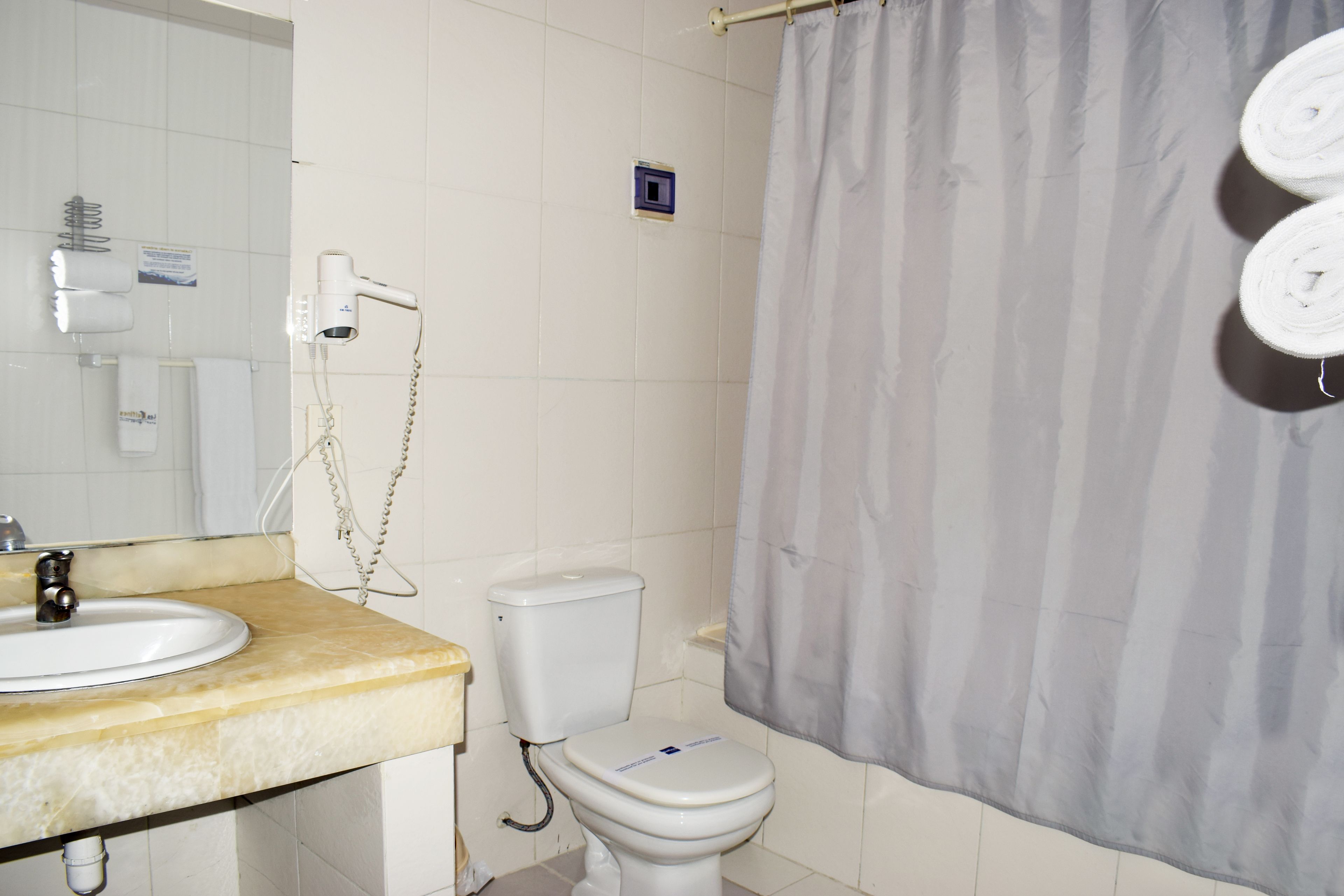 Een badkamer met toilet, wastafel en douchegordijn.