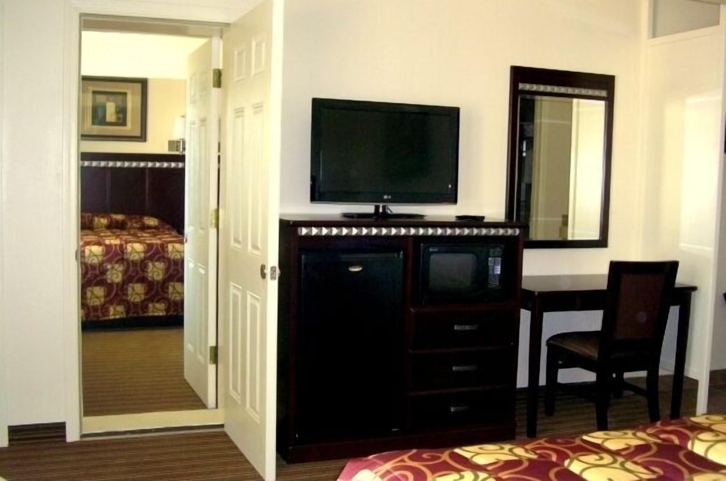 Une chambre d’hôtel avec un lit, une télévision, un miroir et un bureau.