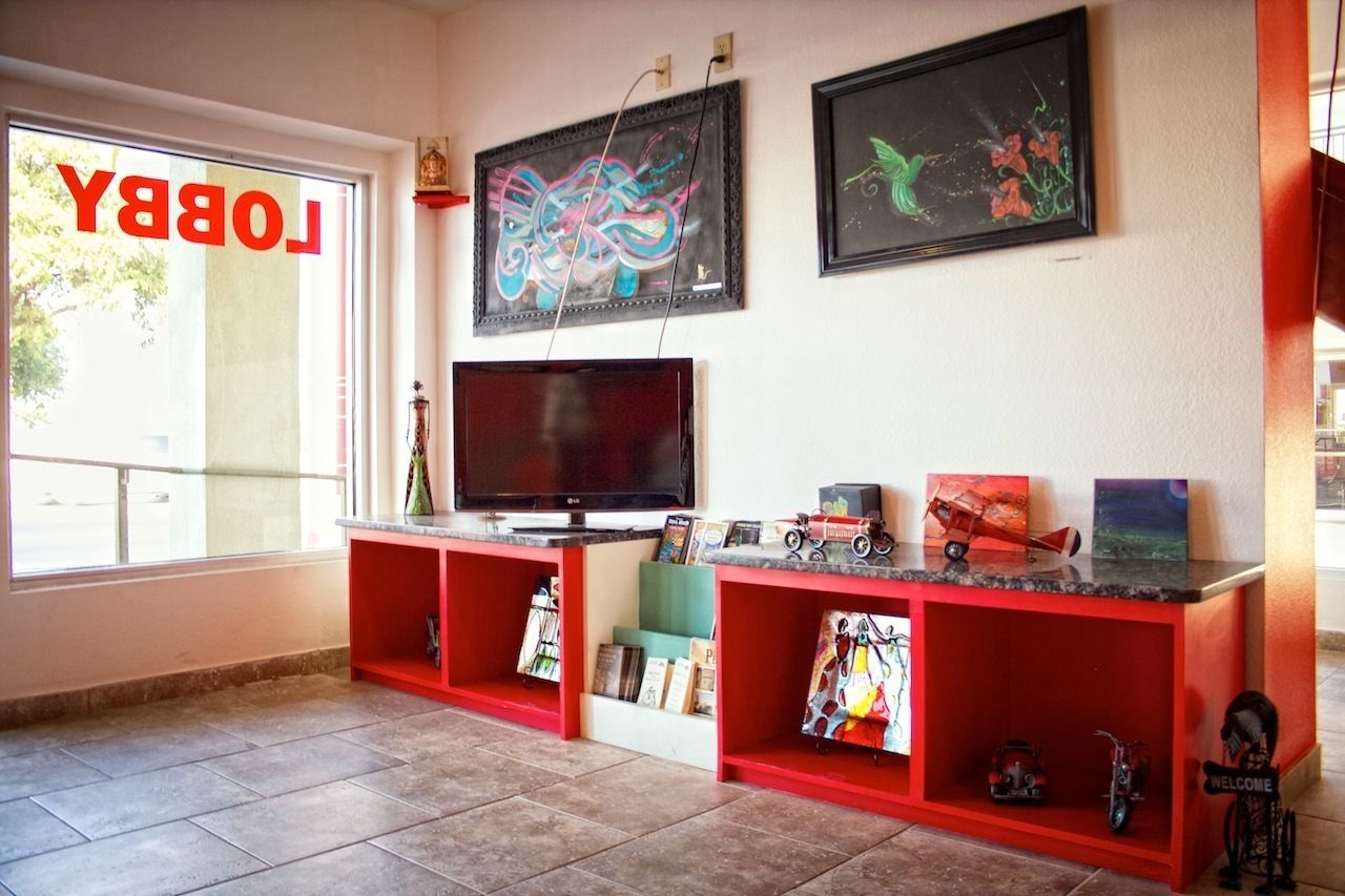A room with a television on a red stand, bookshelves with various items, and two framed artworks on the wall.
