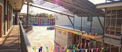 A hotel lobby with a covered outdoor area, a car parked outside, and colorful flags.