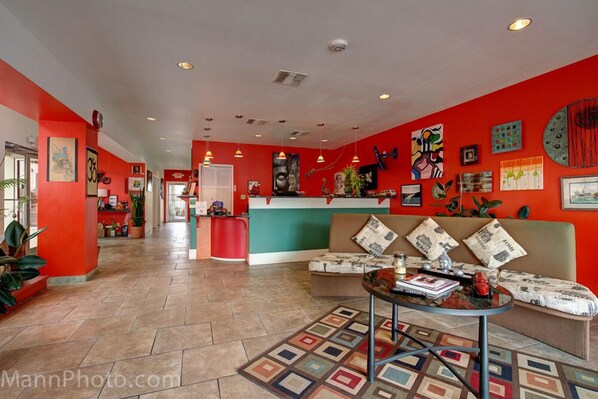 Un vestíbulo de hotel con una decoración en rojo y blanco, una recepción, un sofá y una mesita de centro.