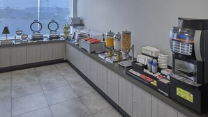 Una barra de desayuno con diversos alimentos y una máquina de café.