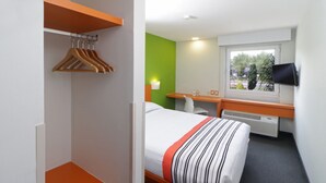Una habitación de hotel con cama, escritorio, televisión y ventana.