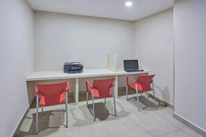 Une pièce avec un bureau, deux chaises rouges et deux ordinateurs portables.