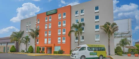 Un hotel City Express Junior by Marriott con un estacionamiento y una camioneta amarilla.