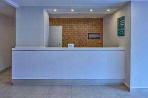 Una recepción con un panel de pared de madera, un letrero con el nombre del hotel y un cartel con tarifas de habitaciones.