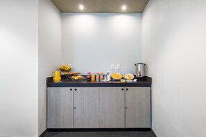 Una kitchenette con encimera, armarios y diversos alimentos.