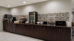 A modern kitchen with dark wood cabinets, a coffee station, a microwave, and a glass-fronted refrigerator. - Best Western SeaWorld San Antonio (San Antonio)