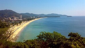 A coastal landscape with a sandy beach, clear blue waters, and a hilly backdrop. - Phunawa Resort Karon Beach Phuket (Karon)