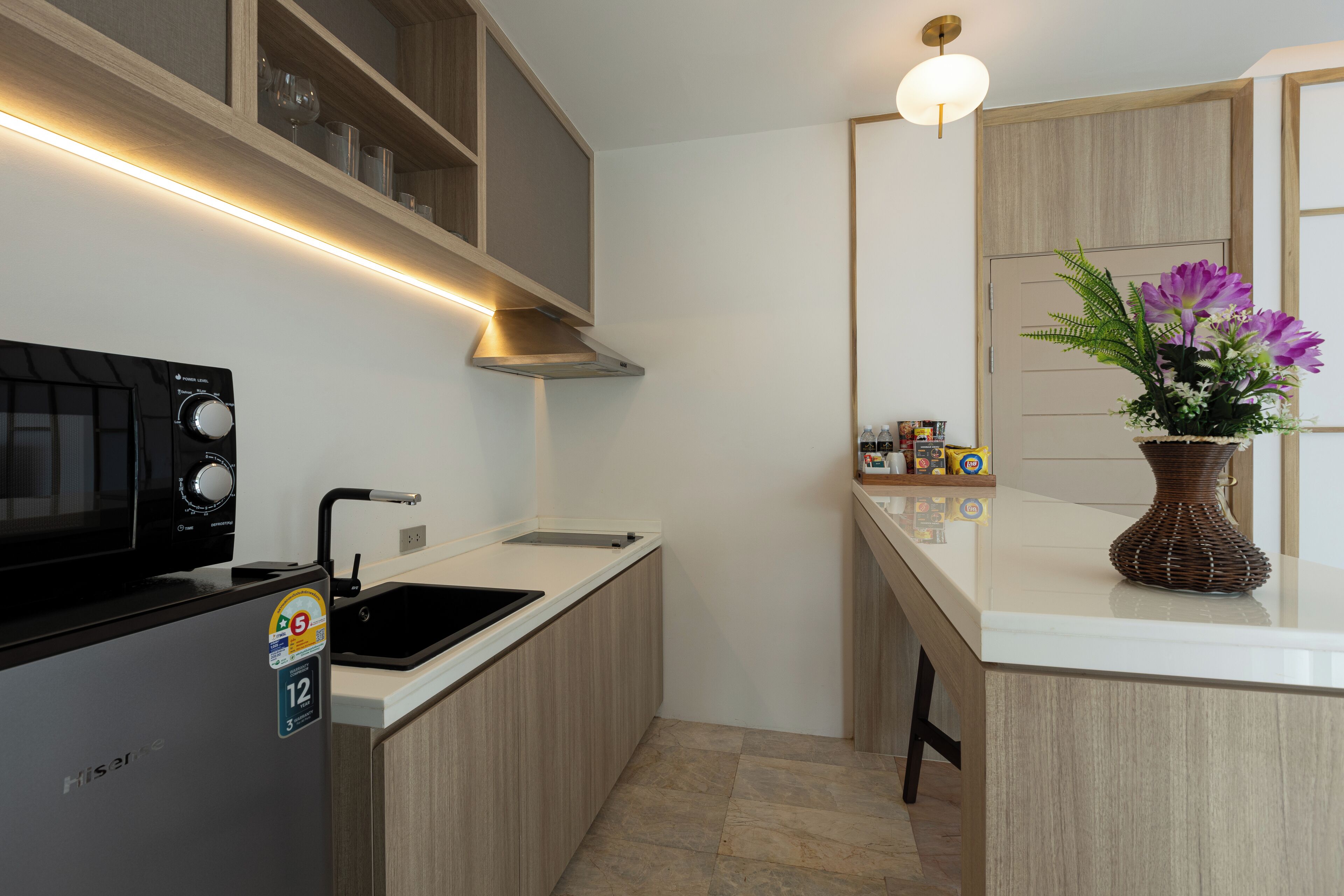 A modern kitchen with a built-in microwave, a sink, and wooden cabinetry.