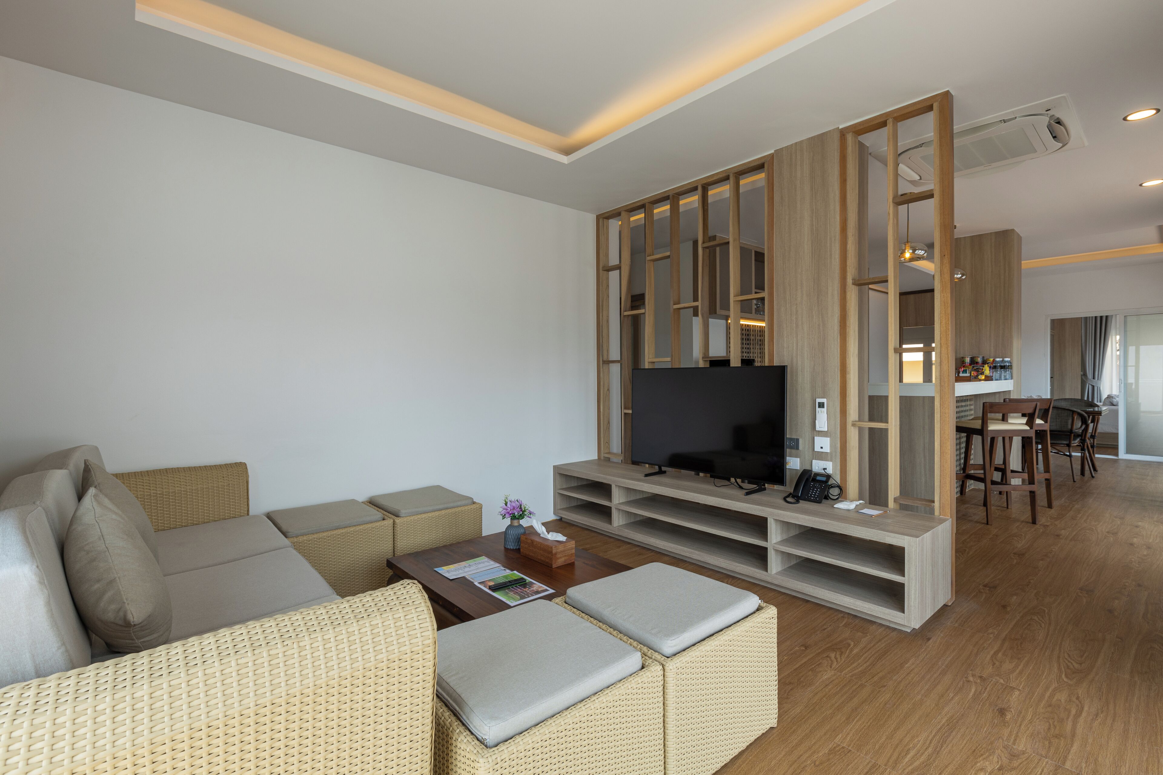 A modern living room with a sofa, TV, and wooden entertainment unit.